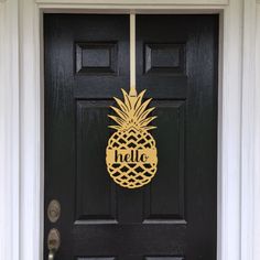 a black front door with a pineapple sign hanging on it's side panel