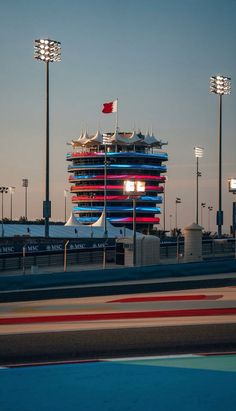 a large building with many lights on it's sides next to a race track