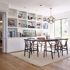 a dining room table and chairs with bookshelves in the background