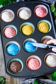 someone using a knife to decorate cupcakes in muffin tins