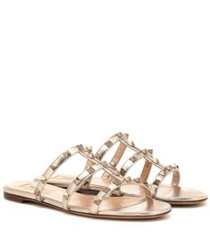 Embrace the fuss-free sandal silhouette of the season with Valentino Garavani's Italian-made Rockstud leather sandals. Presented in glamorous golden leather, this flat style works a caged design that is uplifted by metallic pyramid stud embellishments. Let yours ground bold color palettes and monochrome ensembles alike. Fashion Sandals Flat, Valentino Sandals, Street Style Fall Outfits, Valentino Garavani Shoes, Shearling Slippers, Ancient Greek Sandals, Valentino Rockstud, Valentino Shoes, Slides Sandals