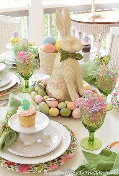 an easter table setting with bunny figurines and cupcakes