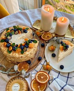 there is a cake with blueberries and oranges on the table next to candles