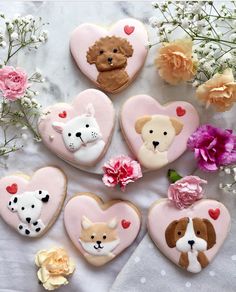 decorated heart shaped cookies with dogs, cats and hearts on them next to pink flowers