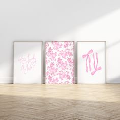 three pink and white wall art prints on a wooden floor in an empty room with sunlight coming through the window