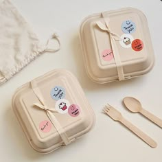 two plastic containers with stickers on them next to utensils and napkins