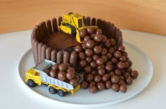 a cake with chocolate candies and construction vehicles on it, sitting on a plate