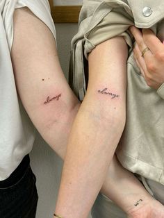 two people with tattoos on their arms and one is holding the other's arm