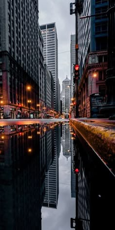 a city street with tall buildings reflecting in the water