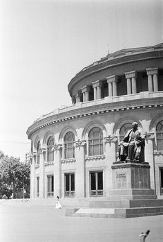 an old black and white photo of a building with a statue in front of it