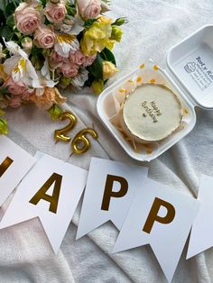 a table topped with flowers and cake on top of a white cloth next to bunting