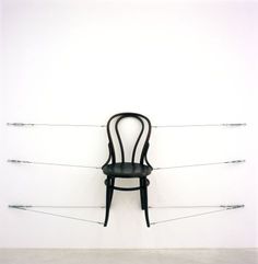 a black chair sitting on top of a white floor next to a wall with wires attached to it