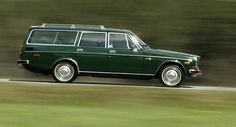 an old green station wagon driving down the road