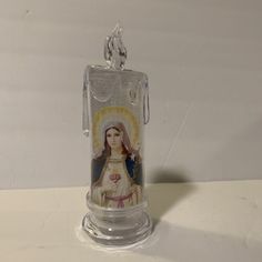 an image of the virgin mary in a glass container on a white surface with a keychain