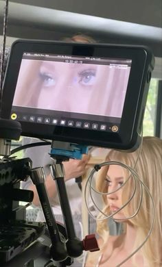 a woman with long blonde hair is looking at an image on her tabletop while another person stands in the background