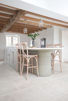 a kitchen with an island and chairs in the center, surrounded by wooden beams on the ceiling