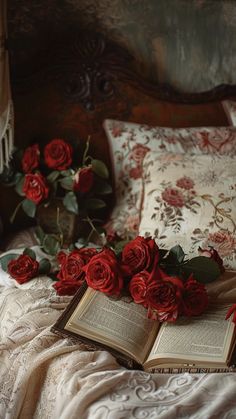 an open book on a bed with red roses