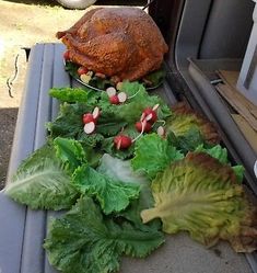 lettuce and other vegetables sit in the back of a car, next to a turkey