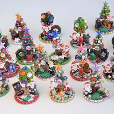 there are many small christmas trees on this white table top, all decorated in different styles and colors