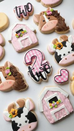 decorated cookies with farm animals and numbers are displayed on a white tablecloth covered surface