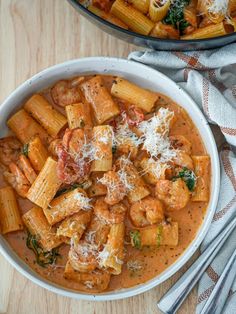 two bowls filled with pasta and sauce on top of a wooden table