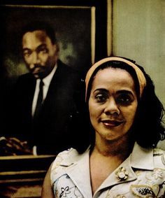 a woman standing in front of a portrait of a man