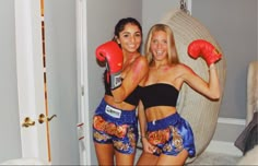 two women wearing boxing gloves pose for a photo