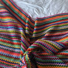 a multicolored crocheted blanket laying on top of a bed