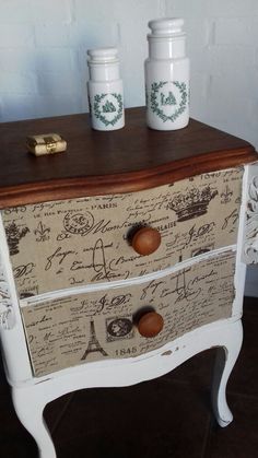 an old dresser has two jars on it