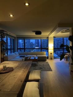 a living room filled with furniture next to large windows and a wooden table in front of it