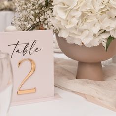 the table numbers are displayed in front of white flowers and wine glasses on a table