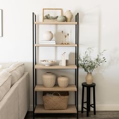 a shelf with vases and other items on it next to a couch in a living room