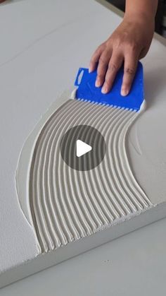 a person is using a blue brush to clean the surface of a white piece of furniture