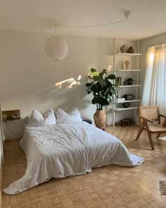 a white bed sitting in a bedroom on top of a hard wood floor next to a window