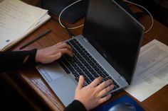 a person using a laptop computer on a wooden desk