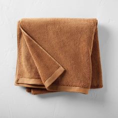 a brown towel hanging on the wall next to it's folded end and edge