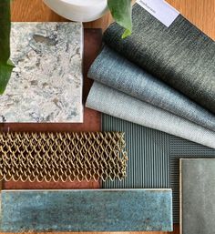 several different types of tile laid out on top of a wooden table next to a potted plant