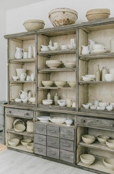 an old wooden cabinet filled with lots of dishes and bowls on top of it's shelves