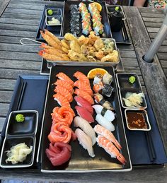 an assortment of sushi on black trays