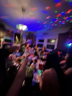 a group of people sitting at a table in a room with colorful lights on the ceiling