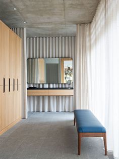 a room with a bench, mirror and closets on the wall next to it