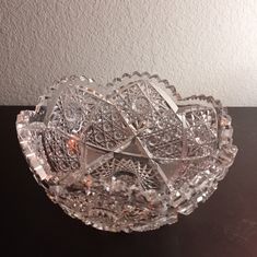 a clear glass bowl sitting on top of a black table next to a white wall