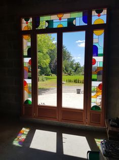 the sun is shining through stained glass windows in an empty room with a potted plant on the window sill