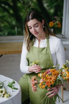 a woman in an apron is arranging flowers