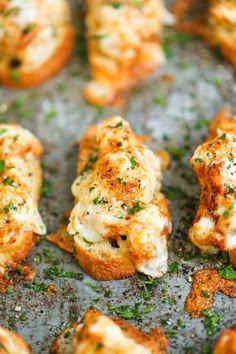 several pieces of bread with cheese and herbs on them sitting on a baking sheet, ready to be eaten