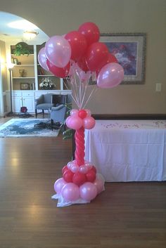 a table topped with lots of balloons on top of a hard wood floor next to a white table cloth