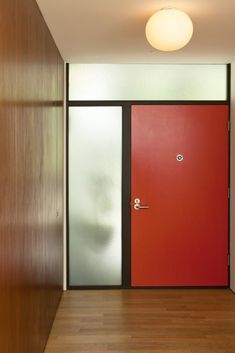 an empty hallway with two red doors and wooden floors