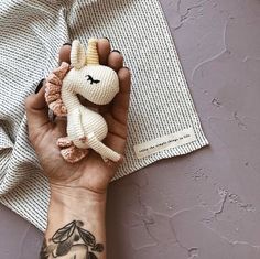 a person's hand holding a small stuffed animal