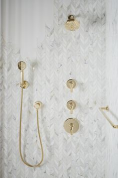 the bathroom is decorated in white and gold with herringbone tile on the shower wall