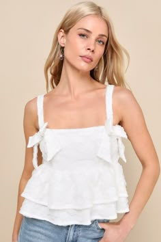 Elevate any outfit to ""adorable"" status with the Lulus Luxe Charisma White Textured Tiered Cropped Sleeveless Bow Top! Lightweight mesh fabric boasts a unique crinkled texture as it shapes adjustable straps that support a cropped bodice with flattering bust seaming and decorative bow details at the straight neckline. Tiered, slightly cropped ruffled hem completes the look. Fit: This garment fits true to size. Length: Size medium measures 11.5" from shoulder to hem. Bust: Great for any cup size Bow Tops Outfit, Fancy White Tops, Black Going Out Tops, Senior Outfits, White Tops Outfit, Senior Szn, Cute White Tops, Rush Outfits, Nashville Outfits